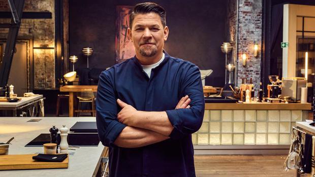 Ein Mann in einem dunklen Kochhemd steht mit verschränkten Armen in einer modernen Restaurantküche. Die Umgebung ist stilvoll mit industriellen Elementen wie freiliegenden Backsteinwänden und modernen Lampen gestaltet. Im Hintergrund sind Küchengeräte und Utensilien zu sehen, die eine professionelle Atmosphäre schaffen.
#!#
Koch,Restaurant,Küche,industriell,modern,Kochhemd,Backstein,Lampen,Küchengeräte,Atmosphäre