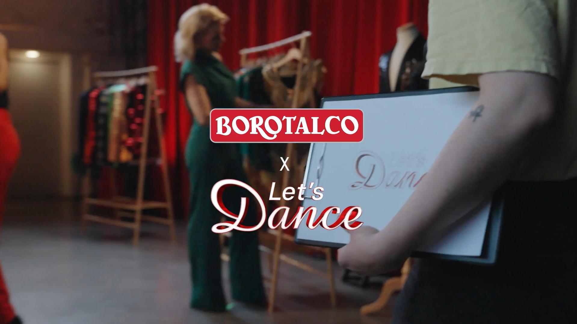 Das Bild zeigt eine Zusammenarbeit zwischen Borotalco und der Tanzshow Let's Dance. Im Vordergrund hält eine Person ein Schild mit dem Schriftzug 'Let's Dance'. Im Hintergrund sind mehrere Kleiderständer mit bunten Kostümen zu sehen, die vermutlich für eine Tanzaufführung vorbereitet werden. Eine Person in einem grünen Outfit betrachtet die Kostüme. Der Raum hat einen industriellen Look mit roten Vorhängen.
#!#
Borotalco,Let's Dance,Kollaboration,Tanzen,Kostüme,Vorbereitung,Show,Hintergrund,Mode,Entertainment