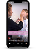 Das Bild zeigt eine Frau, die einer anderen Frau professionell Make-up aufträgt. Sie befinden sich in einem gut beleuchteten Raum, und die visuelle Darstellung erfolgt auf einem Smartphone-Bildschirm. Der Text auf dem Bildschirm weist auf eine Kooperation mit einer Marke hin und erwähnt ein Hochzeitsthema. Die Szene wirkt ruhig und konzentriert, während die Visagistin sorgfältig die Augenpartie der Kundin bearbeitet.
#!#
Make-up,Hochzeit,Visagistin,Tutorial,Herbst,Kooperation,Smartphone,Kundin,Pflege,Event